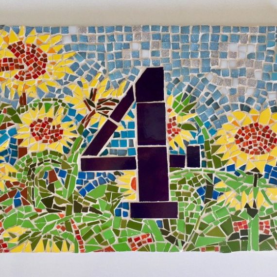 Placa de entrada em mosaico de vidro com número e girassóis.